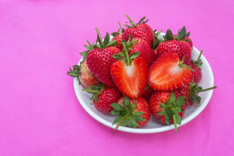草莓甜蜜的红色的水果seed-studded表面集团红色的浆果心形的水果白色板粉红色的织物