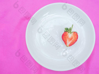 单红色的心草莓甜蜜的水果特写镜头纹理红色的浆果心形的水果一半减少白色板粉红色的织物背景