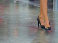 关闭女腿步骤穿高高跟鞋优雅的鞋子混凝土地板上