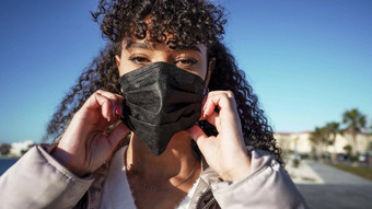 关闭肖像年轻的非洲美国女人穿黑色的面具避免冠状病毒感染户外正常的社会行为人类城市流感大流行疾病