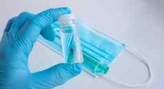 blue-gloved手持有瓶疫苗概念冠状病毒医学药物