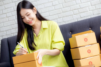 年轻的亚洲女人写作地址包裹盒子<strong>首页</strong>交付订单客户航运<strong>物流</strong>商人在线卖方业务老板锻造在线购物电子商务