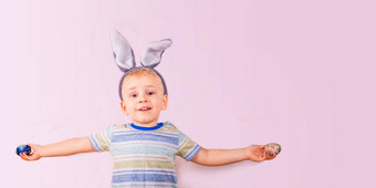 可爱的婴儿男孩兔子兔子耳朵<strong>头彩</strong>色的鸡蛋粉红色的背景复活节假期横幅