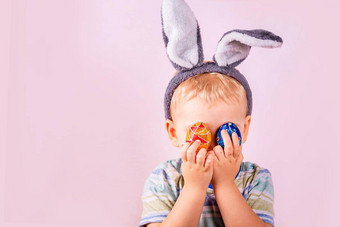 可爱的婴儿男孩<strong>兔子兔子</strong>耳朵头关闭<strong>眼睛</strong>彩色的鸡蛋粉红色的背景复活节假期