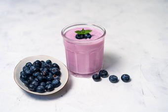 美味的新鲜的<strong>蓝莓酸奶</strong>摇甜点玻璃站白色表格背景