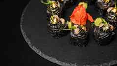 寿司卷紫菜黑色的大米蟹肉黄瓜鳄梨烟熏大马哈鱼摩丝桨鱼子酱大规模虾鸡尾酒可食用的黄金叶红色的姜芥末酱黑色的表格背景