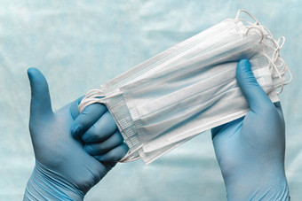 医生持有很多医疗脸面具手蓝色的医疗手套显示拇指流感大流行保险流感机载疾病“非典”