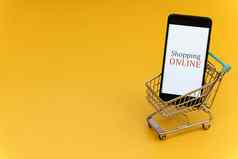 购物车智能手机黄色的背景在线购物概念