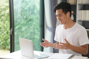 亚洲年轻的学生男人。企业家穿耳机工作视频调用会议研究学习在线首页电子学习网络研讨会会议社会距离科维德流感大流行