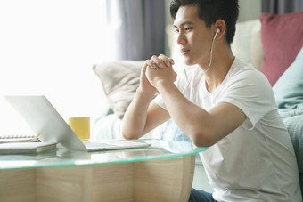 亚洲年轻的学生男人。企业家穿耳机工作电脑研究学习在线首页电子学习网络研讨会会议社会距离科维德流感大流行