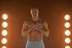 活跃的生活方式概念专业健美运动员显示ABS肌肉相机灯照明烟背景
