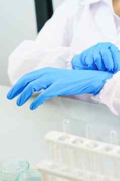 科学家手把腈蓝色的乳胶手套labcoat穿腈手套