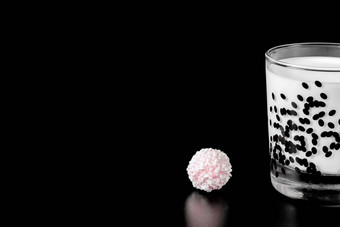 玻璃牛奶粉红色的糖果黑色的背景健康食物隔离