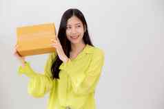 年轻的亚洲女人微笑持有纸板盒子惊喜首页快乐女携带包裹盒子兴奋现在礼物包装交付在线购物商店服务概念