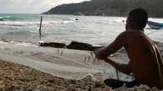 KOHPhangan泰国1月少数民族渔夫挂诱饵网一边视图少数民族赤膊上阵男人。挂小鱼网坐着海岸海