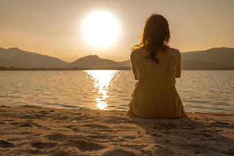 认不<strong>出来</strong>孤独的沉思的女人坐着沙子海滨设置<strong>太阳</strong>光反射水橙色乌贼古董摄影效果做梦人黎明