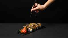 手黑色的筷子自定义寿司卷墨鱼墨水大马哈鱼奶油奶酪胡椒南瓜鳗鱼可食用的黄金叶姜芥末酱广场板黑色的表格