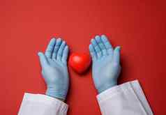 手蓝色的乳胶手套持有红色的心捐赠概念