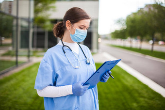 女国民健康保险<strong>制度</strong>医生持有蓝色的剪贴板站医院诊所街入口