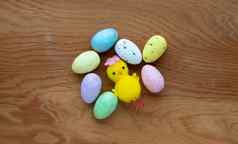 色彩斑斓的复活节玩具鸡蛋黄色的玩具鸡木背景概念复活节