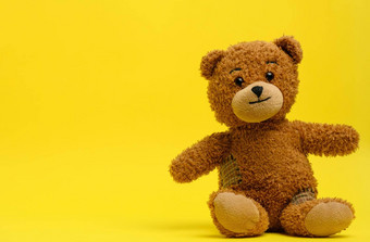 棕色（的）泰迪熊坐在黄色的背景
