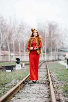 年轻的女孩红色的头发明亮的红色的衣服铁路跟踪