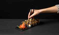 手黑色的筷子自定义寿司卷墨鱼墨水大马哈鱼奶油奶酪胡椒南瓜鳗鱼可食用的黄金叶姜芥末酱广场板黑色的表格