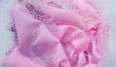 粉红色的衣服浸泡粉洗涤剂水解散洗衣概念