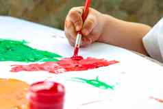 孩子的手持有刷油漆纸大中风涂片明亮的油漆白色纸