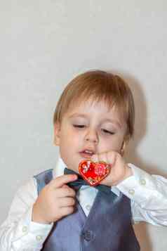 男孩持有手红色的心概念情人节一天主题肖像可爱的男孩西装弓领带