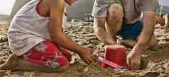 裁剪照片男孩父亲建筑沙子城堡海滩