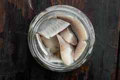 大西洋野生鲱鱼腌罐头鱼保存玻璃Jar黑暗木表格背景前视图平躺