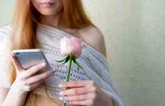 女人持有智能手机粉红色的玫瑰