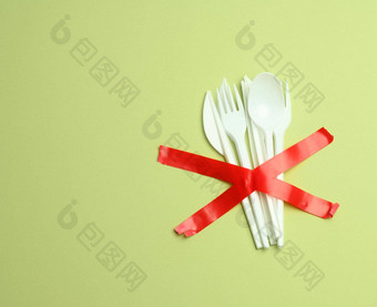 塑料叉勺子粘红色的磁带绿色背景避免塑料