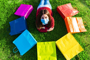 快乐美丽的女孩医疗保护面具铺设草草地相机虹膜彩色的购物袋圆概念信任未来生活正常的生活