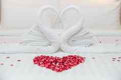 天鹅毛巾床上玫瑰花瓣心形状度蜜月婚礼周年纪念日浪漫的感觉
