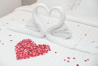 天鹅毛巾床上玫瑰花瓣心形状度蜜月婚礼周年纪念日浪漫的感觉