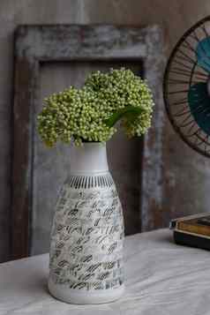 花束绿色花白色手工制作的陶瓷花瓶瓶形状古董风扇白色变形表格布水泥墙