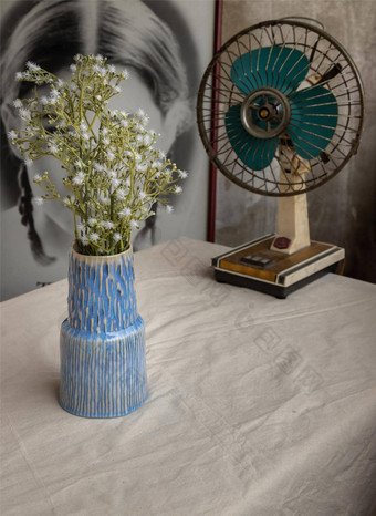 花束白色花蓝色的手工制作的陶瓷花瓶古董风扇白色变形表格布前面经典中国人海报电影框架水泥墙