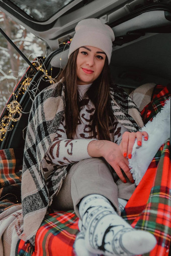 浅黑肤色的女人女人包装毯子树干车喝咖啡茶热水瓶旅行冬天车装饰节日圣诞节灯户外野餐