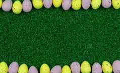 色彩斑斓的黄色的粉红色的复活节蛋雀斑模式草复制空间