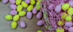 色彩斑斓的黄色的粉红色的复活节蛋雀斑模式木表格复制空间粉红色的黄色的复活节蛋内部篮子