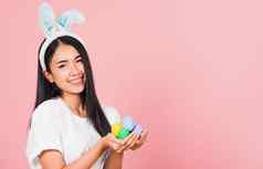 女人微笑穿兔子耳朵持有色彩斑斓的复活节鸡蛋礼物手