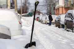 大黑色的塑料雪铲白雪覆盖的汽车阳光明媚的冬天早....
