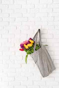 灰色的波尔卡点织物袋完整的色彩斑斓的郁金香白色砖背景