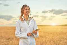 女人农民白色外套聪明的农业站农田微笑数字平板电脑女农学家专家研究监控分析数据农业综合企业