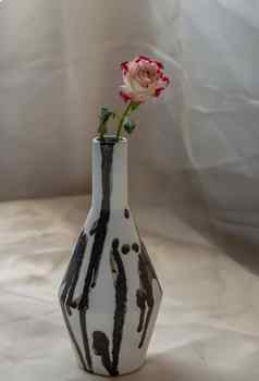 粉红色的花黑色的白色手工制作的陶瓷花瓶脸红变形表格布