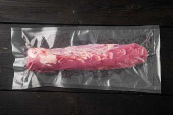 真空包装肉产品猪肉角里脊肉黑色的木表格背景前视图平躺