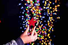 持有圣诞节闪光的明星装饰孤立的背景模糊灯12月季节圣诞节作文