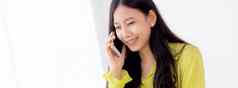 年轻的亚洲业务女人工作形式首页办公室调用电话成功首页女商人移动PC电脑桌子上女会说话的智能手机工作场所沟通概念